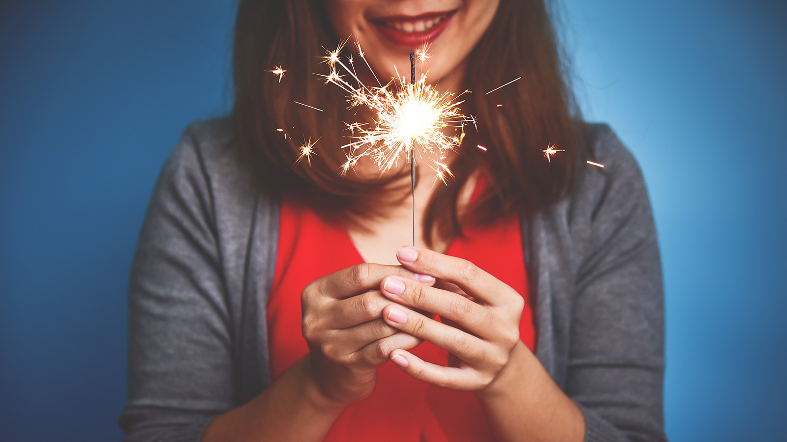 Woman smiling while holding a single sparkler