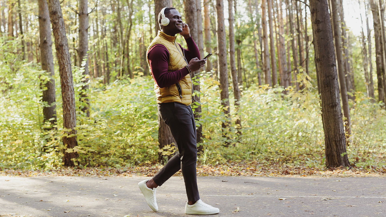 A man listening to headphones while vigorously walking in the woods