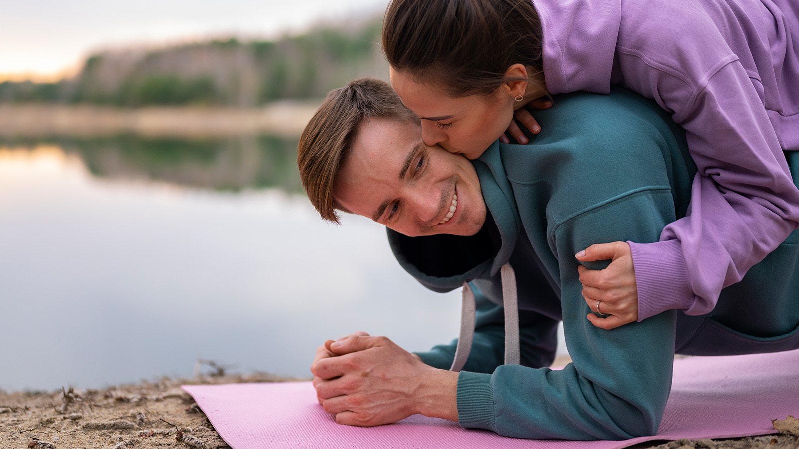 Man does a yoga position while being embraced by woman